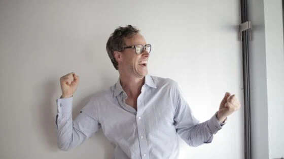 a man in a white shirt and glasses standing in front of a white wall