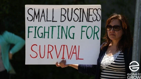 a woman holding a sign that says small business fighting for survival